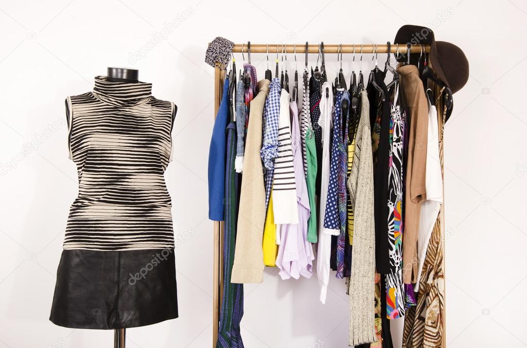 Dressing closet with colorful clothes arranged on hangers and an outfit on a mannequin.
