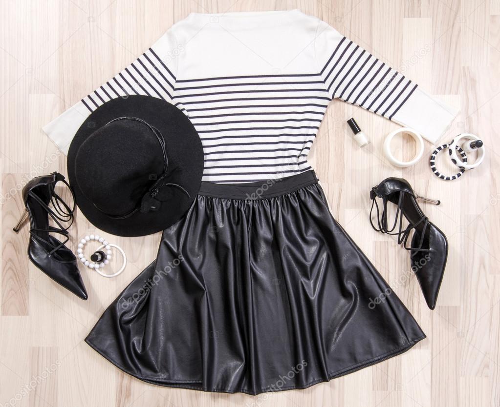 Striped blouse and leather skirt with accessories arranged on th