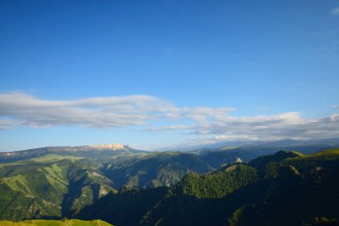 Akşam dağlarının Panorama 'sı Pinus kochiana dağı ve mavi gökyüzü ile kaplı yüksek dağlık Shijatmaz platosundan Kuzey Kafkasya dağları                               