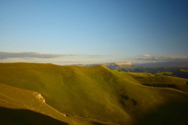 Kuzey Kafkasya dağlarındaki yüksek dağlık Shidzhatmaz platosundan gün batımında Kafkasya dağlarının ve bulutların manzarası                               