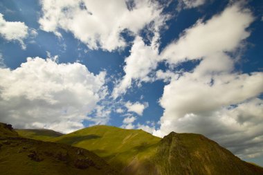  Kuzey Kafkasya 'daki Dzhily-Su geçidinde mavi gökyüzü ve bulutlu Kafkas dağlarının panoraması
