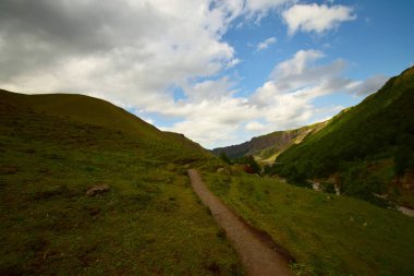 Kuzey Kafkasya 'daki Dzhily-Su geçidinde mavi gökyüzü ve bulutlarla akşam Alp Kafkas dağlarının manzarası