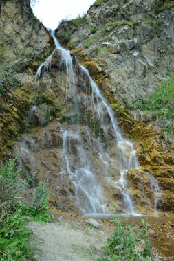 Kuzey Kafkasya 'da yaz mevsiminde Kafkasya yaz şelalesinin Dzhily-Su arazisinde bitki örtüsü olan bir kayadaki görüntüsü.                               
