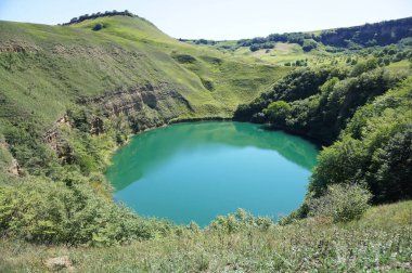 Kuzey Kafkasya dağlarındaki Kabardino-Balkaria 'nın Zolsky bölgesinde yaz aylarında mavi su ve yeşil bitki örtüsüyle Alp Gölü Panoraması                              