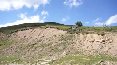 Kuzey Kafkasya 'daki Dzhily-Su yolunda giderken mavi gökyüzü ve bulutlu Kafkasya dağları ve tepeleri manzarası.