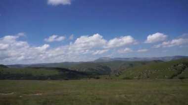 Kuzey Kafkasya 'daki Dzhily-Su yolunda araba sürerken mavi gökyüzü ve bulutlu Kafkas dağlarının panoraması. 