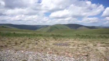 Kuzey Kafkasya 'daki Dzhily-Su yolunda giderken mavi gökyüzü ve bulutlu Alp Kafkas dağlarının panoraması.