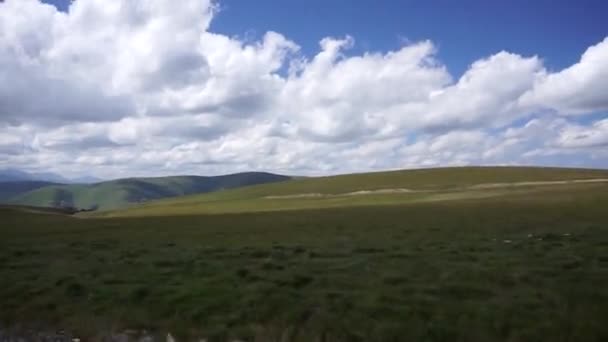 北コーカサスのDzhily Su道路沿いの車に乗っている間 青い空と雲のあるアルパイン コーカサス山脈の景色 — ストック動画