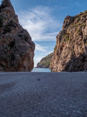 Alacakaranlıkta Mallorca 'da Sa Calobra plajı. Yükselen uçurumlar arasında uzanan sakin sahil. Ufuk çizgisine kadar uzanan deniz.