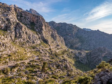 Sa Calobra, Mallorca 'ya giden Serpentine yolu, engebeli dağların arasından geçen dolambaçlı yollar, yeşillik ve açık mavi gökyüzü, Majorca