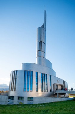 Kuzey Işıkları Katedrali, Alta, Norveç. Uzun, ince kuleli ve geniş pencereli modern kilise berrak mavi bir gökyüzünün altında duruyor.