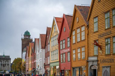 Bryggen, Bergen, Norveç, renkli, geleneksel ahşap binalar, yağmurlu bir günde arka planda tarihi bir kule ile hareketli bir cadde oluşturur.