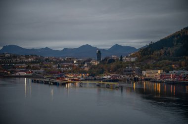 Narvik, Norveç, sakin bir liman şehri, arka planda dağlar ve akşam ışıklarını yansıtan bir rıhtım.