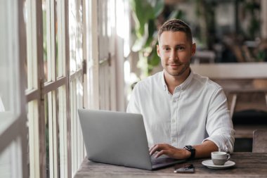 Kafedeki bilgisayarında çalışan genç bir adam.