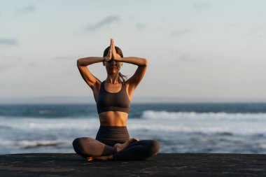 Genç ve güzel bir kadın sahilde meditasyon yapıyor..