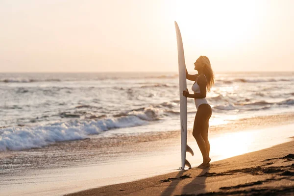 Vacker surfare kvinna på stranden vid solnedgången — Stockfoto