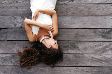 Beyaz elbiseli güzel bir bayanın resmi ahşap zeminde yatıyor, yaz aksesuarları....