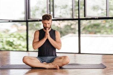 Yogacı adamlar stüdyoda pencerenin önünde egzersiz yapıyor.