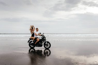 Kumsalda motosiklet süren genç bir çift.
