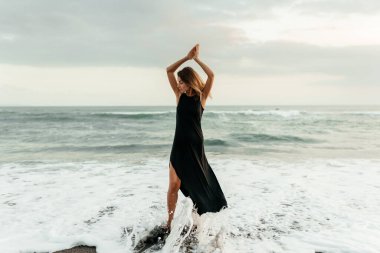 Kumsaldaki kadın, tatil boyunca sakin okyanus doğasının tadını çıkarıyor.