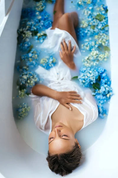 Mulher relaxante no banho com hortênsia azul tropical. — Fotografia de Stock