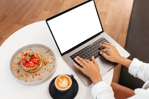 Kadınlar ellerinde laptopla masada lezzetli meyveli kreplerin yanında.