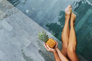 Tanınamayacak kadar zayıf genç bir kadın sulu ananasları elinde tutuyor.