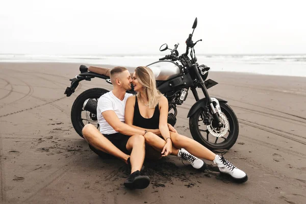 Jóvenes jinetes de pareja juntos en la playa de arena en moto —  Fotos de Stock
