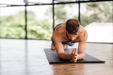 Yogacı adamlar stüdyoda pencerenin önünde egzersiz yapıyor.