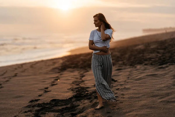 Glückliche Frau genießt schönen Sonnenuntergang am Strand — Stockfoto