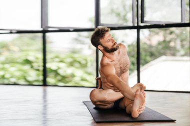 Yogacı adamlar stüdyoda pencerenin önünde egzersiz yapıyor.