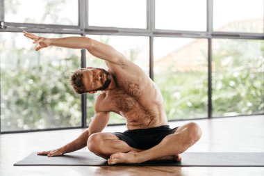 Yogacı adamlar stüdyoda pencerenin önünde egzersiz yapıyor.