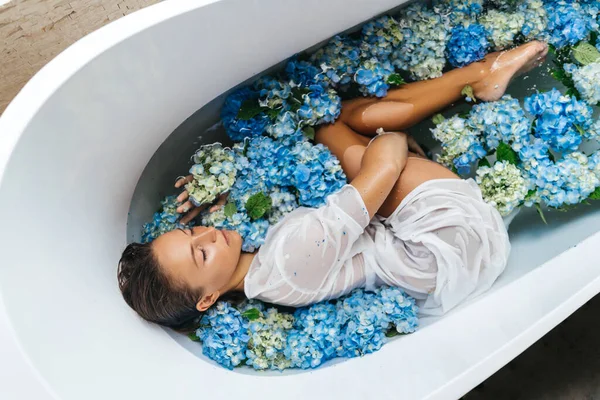 Mujer relajante en baño con hortensias tropicales azules. —  Fotos de Stock