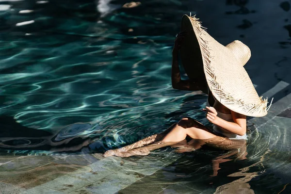 Donna in grande cappello di paglia rilassante in piscina. — Foto Stock