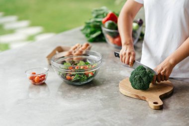 İnsan elleri mutfakta sebze salatası pişiriyor.