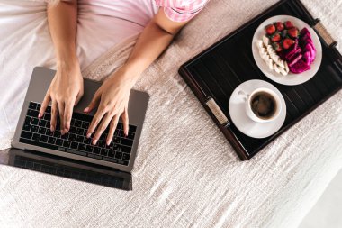 Sabah kahvaltısı sırasında yatak odasında çalışan genç bir kadın.