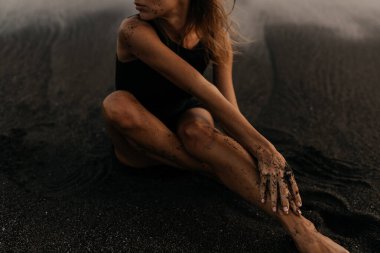 Kumsaldaki kadın, tatil boyunca sakin okyanus doğasının tadını çıkarıyor.