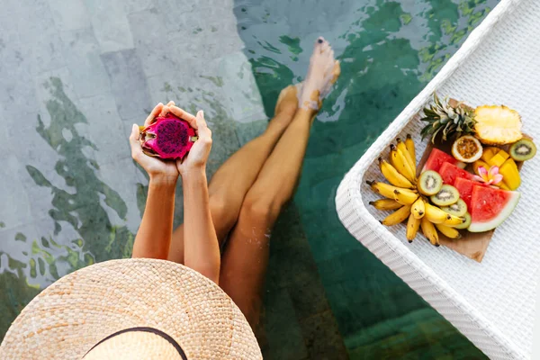 Mulher segurando dragão fruta perto da bandeja com servido Café da manhã na piscina. — Fotografia de Stock