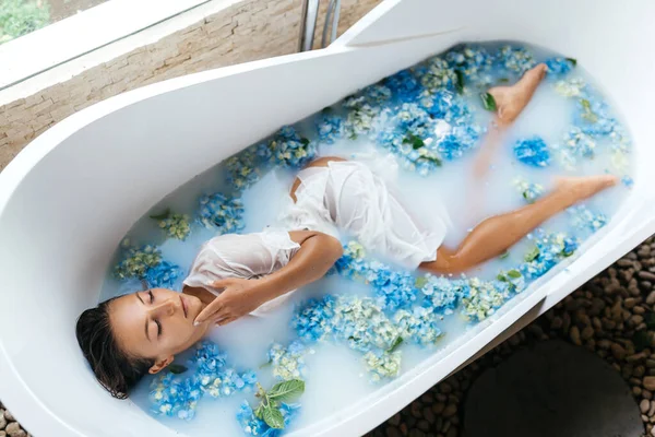 Mulher relaxante no banho com hortênsia azul tropical. — Fotografia de Stock