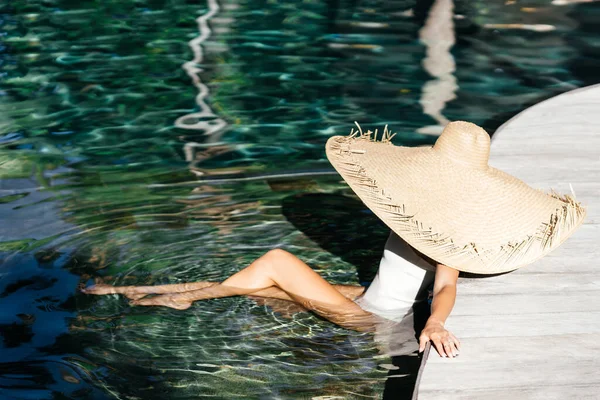 Donna in grande cappello di paglia rilassante in piscina. — Foto Stock