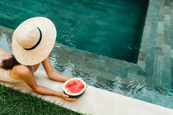 Joven mujer atractiva en la piscina disfrutando de deliciosa sandía madura. —  Fotos de Stock