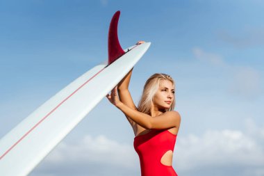 Uzun sarı saçlı sörfçü kadın okyanusa gider..