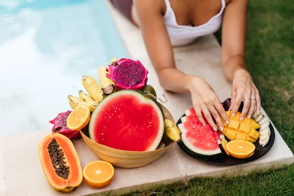 Mulher relaxante e comendo frutas na piscina na villa de luxo em Bali. — Fotografia de Stock