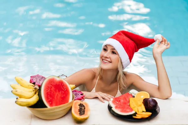 Noël femme beau sourire dans le chapeau Santas avec des fruits tropicaux — Photo