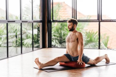 Yogacı adamlar stüdyoda pencerenin önünde egzersiz yapıyor.