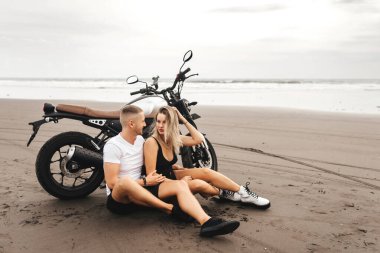 Kumsalda motosikletle gezen genç çiftler.