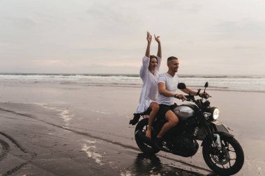 Kumsalda motosiklet süren genç bir çift.