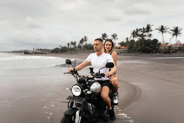 Unga par rider motorcykel på stranden — Stockfoto