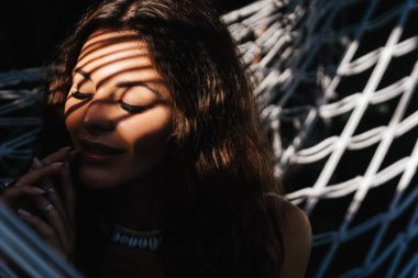 Çekici genç bir kadın hamakta yatarken dışarıda dinleniyor..