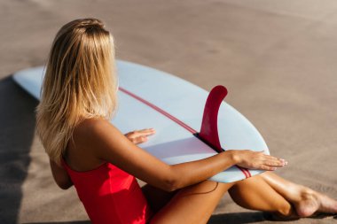 Uzun sarı saçlı sörfçü kadın okyanusa gider..